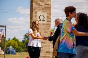 Female student being greeted by Father Tyson in 2019