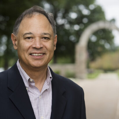 Headshot of Dr. Steve Varela with Holy Cross Arch in the background
