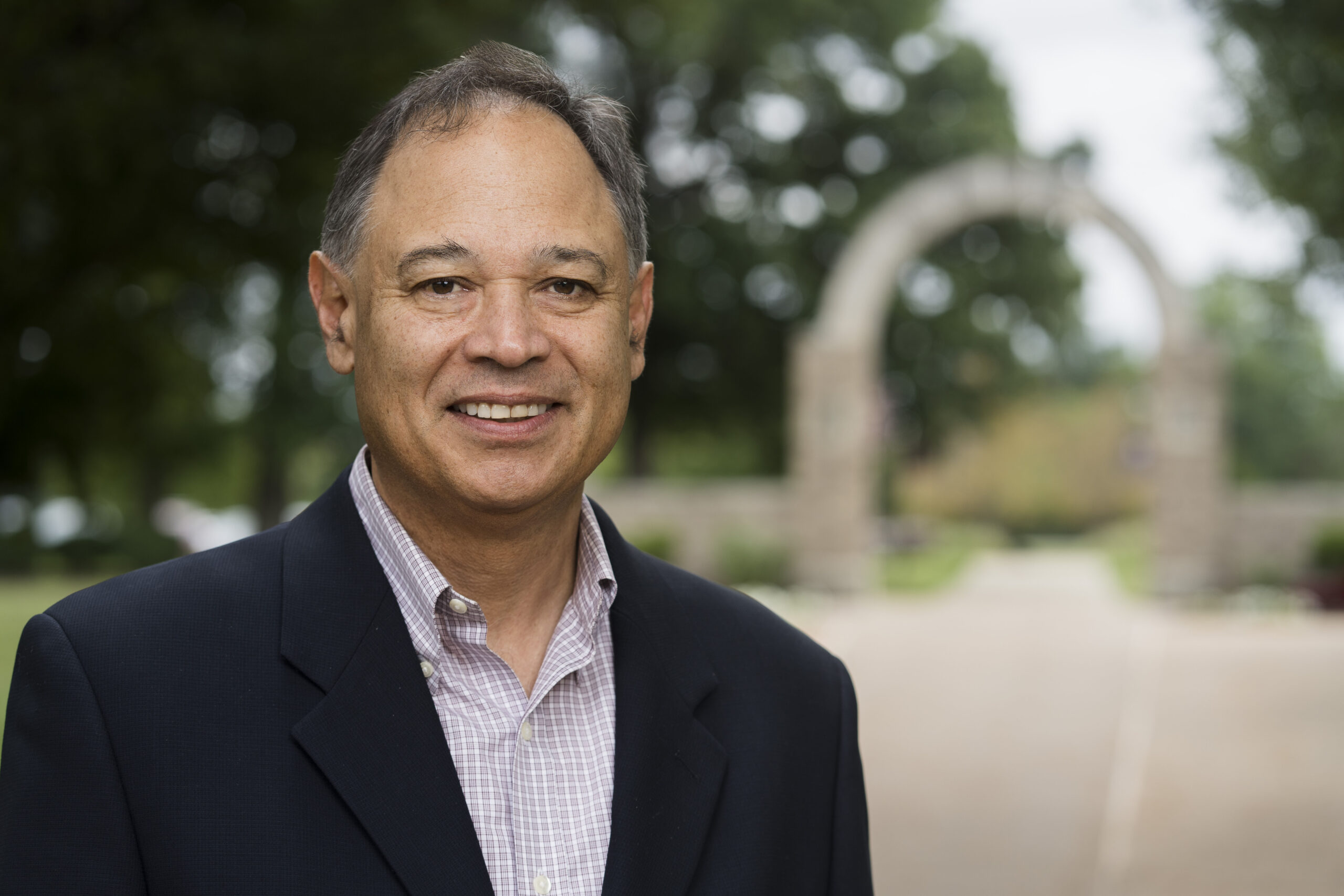 Headshot of Dr. Steve Varela with Holy Cross Arch in the background