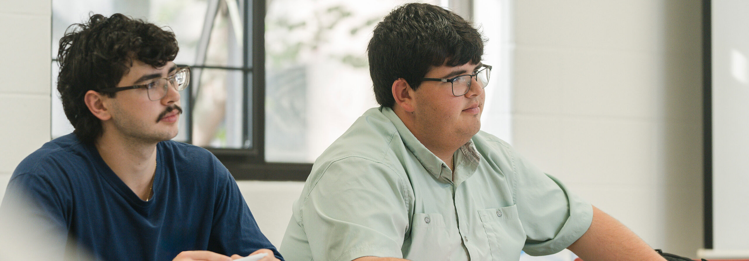 Two students sit side by side in a seminar classroom